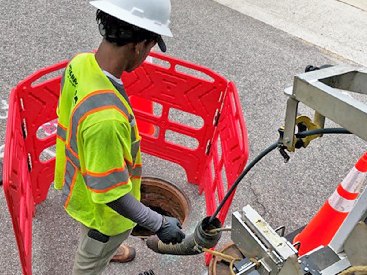 A Hydromax USA worker feeds a sensor down a manhole.